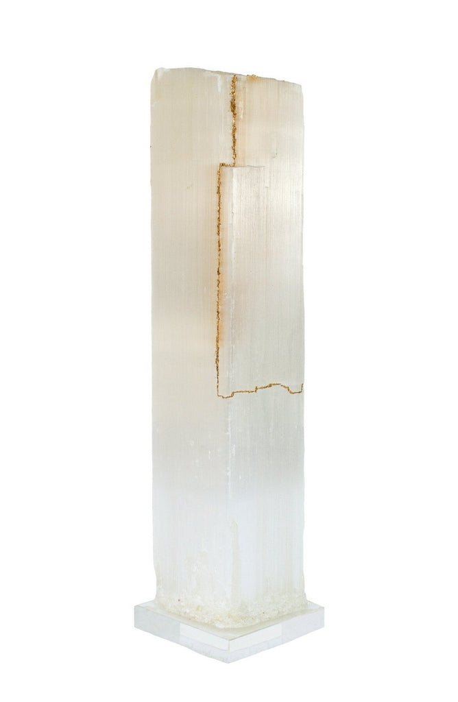 Ruler Selenite with gold leaf on a Lucite base. Selenite logs are single, prismatic selenite crystals from Morocco that were formed in extensive beds by the evaporation of ocean brine. This mineral is characterized by a silky, pearly luster called satin spare. It is then subtly lined with gold leaf on one side which contrasts beautifully with the sleek selenite.