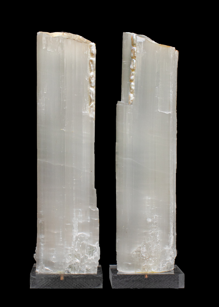 Pair of ruler selenite with natural forming baroque pearls on a lucite base. Ruler selenite or "selenite logs" are single, prismatic selenite crystals from Morocco that were formed in extensive beds by the evaporation of ocean brine. This mineral is characterized by a silky, pearly luster called satin spare. Both are then adorned with the baroque pearls which coordinate beautifully with the sleek selenite.