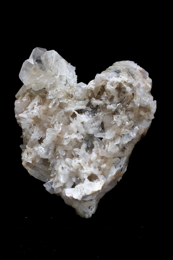 Large white crystal quartz cluster heart. The piece creates an organic sculptural work of art.