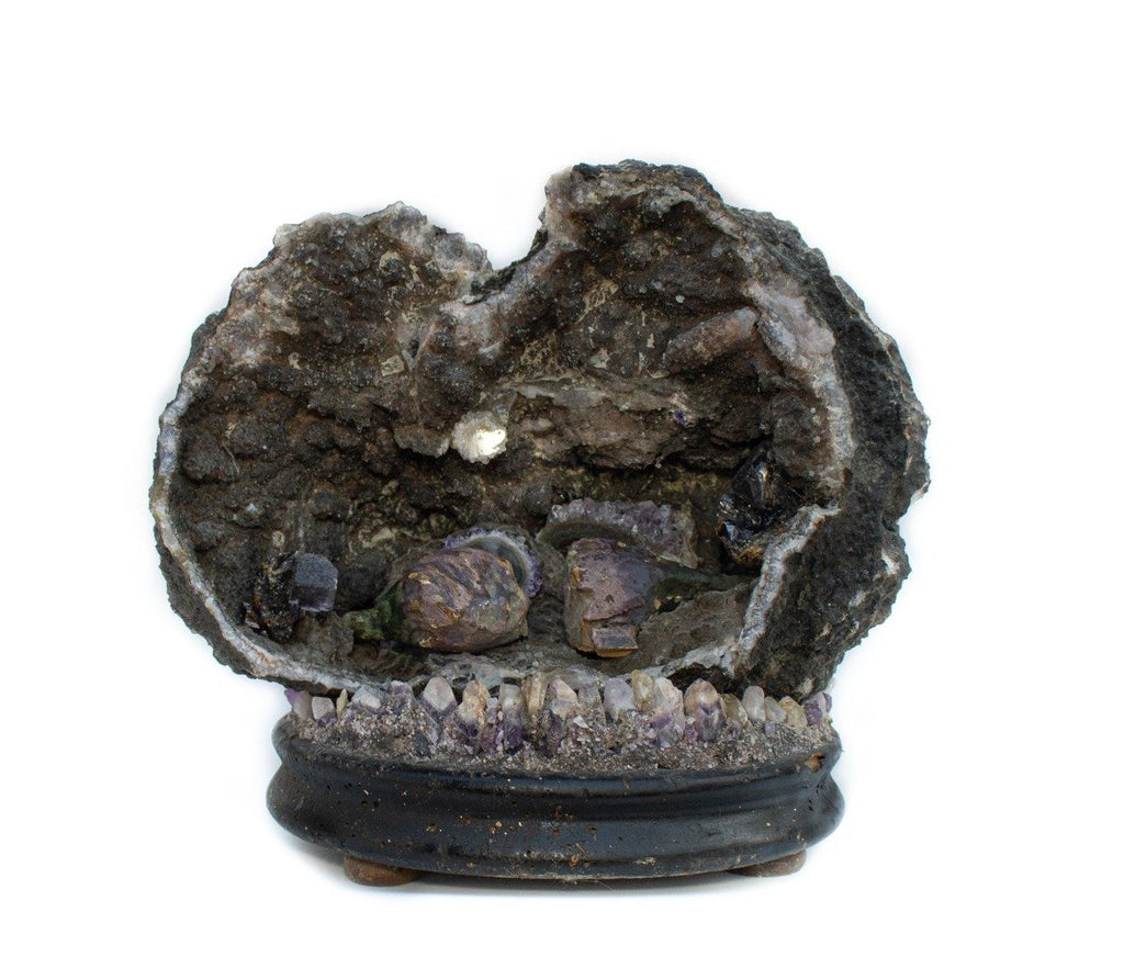 Amethyst geode with amethyst stalagmites and hand-carved and hand-painted 18th century Italian fragment violet flowerbuds on an antique base adorned with amethyst teeth. The sculptural piece is reminiscent of a cave and is a mineralized work of old and new. 